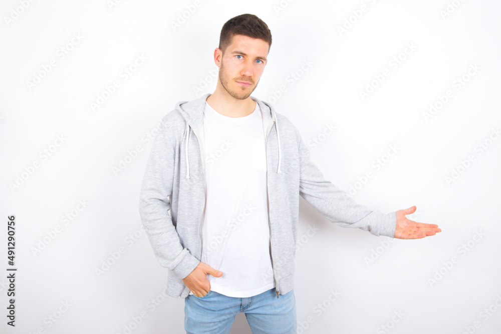 Portrait of young caucasian man wearing casual clothes over white background with arm out in a welcoming gesture. Portrait of young caucasian man wearing casual clothes over white background with arm out in a welcoming gesture.