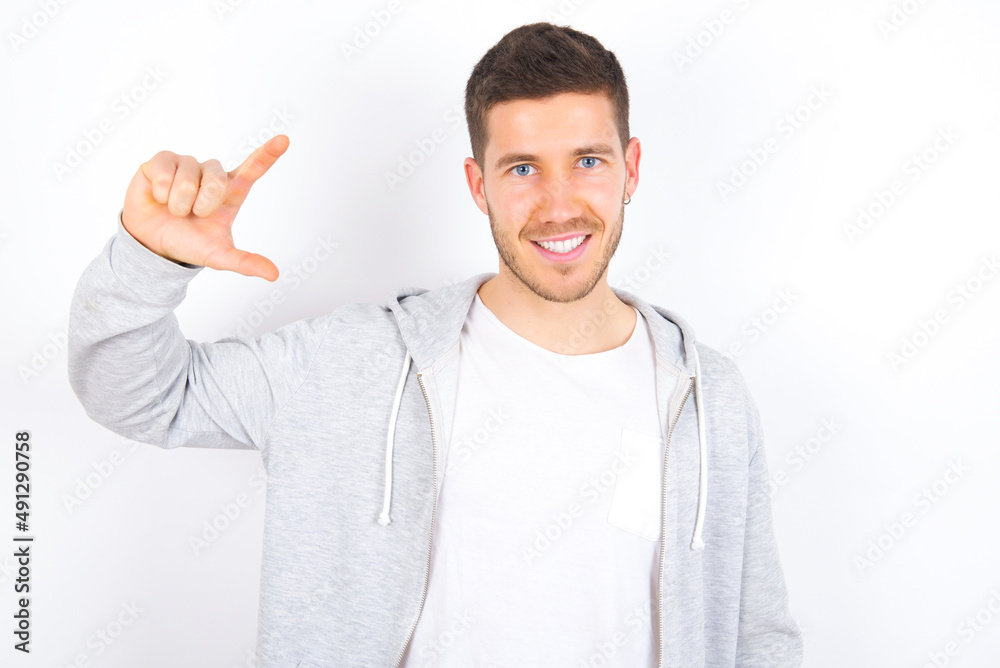 young caucasian man wearing casual clothes over white background smiling and gesturing with hand small size, measure symbol. young caucasian man wearing casual clothes over white background smiling and gesturing with hand small size, measure symbol.