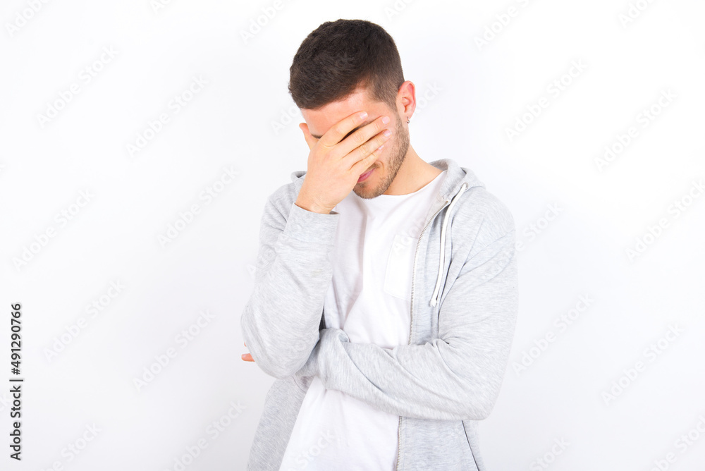 young caucasian man wearing casual clothes over white background making facepalm gesture while smiling amazed with stupid situation. young caucasian man wearing casual clothes over white background making facepalm gesture while smiling amazed with stupid situation.