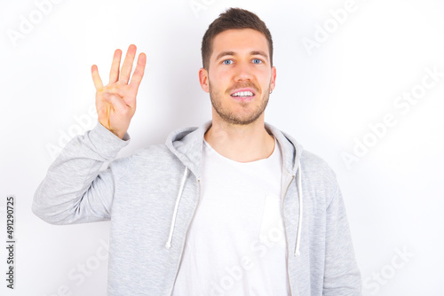 young caucasian man wearing casual clothes over white background showing and pointing up with fingers number four while smiling confident and happy. © Jihan