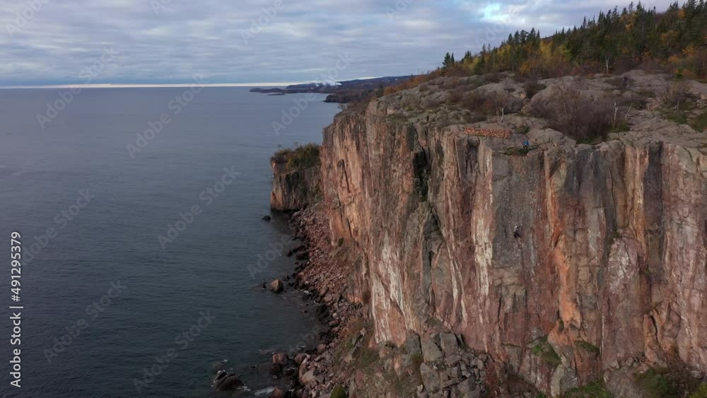 Aerial drone climbing shot of rock cliffs along lake