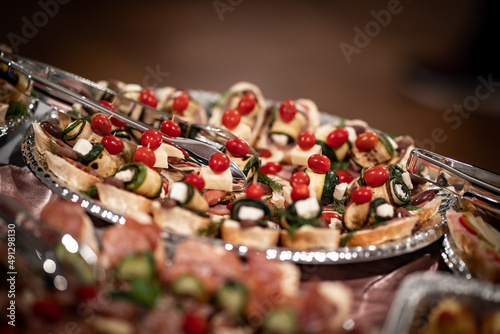 Variety tapas platter arranged in silver colored dish and garnished with cherry tomatoes for catering of an event 