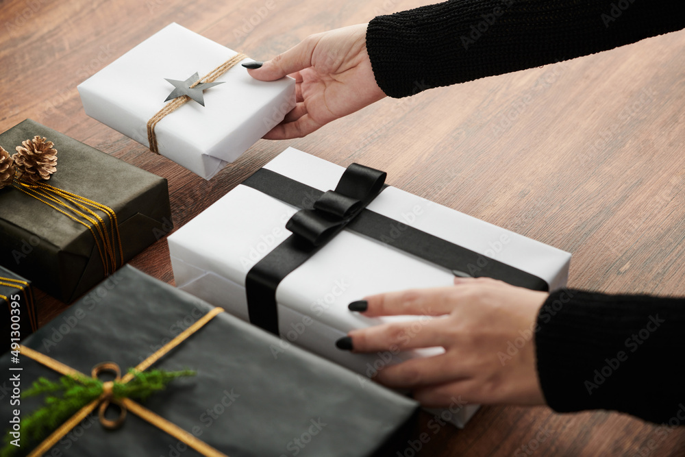 Close-up image of woman putting wrapped presents she bought for friends and family members on table