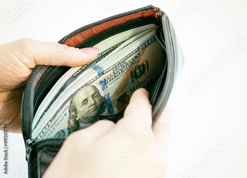 A woman holds an open wallet with dollars in her hands