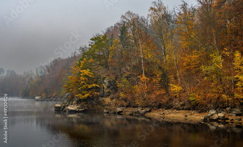 Fototapeta Naklejka Na Ścianę i Meble -  Foggy Landscape With Calm Lake And Autumnal Forest At Lake Ottenstein In Austria