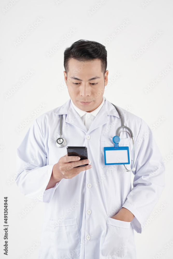 General practitioner in labcoat checking notifications on smartphone General practitioner in labcoat checking notifications on smartphone