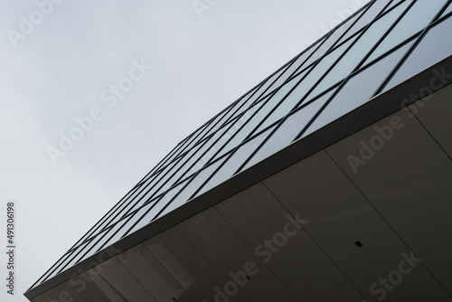 The exterior wall of a contemporary commercial style building with aluminum metal composite panels and dark grey columns. The futuristic building has engineered diagonal cladding steel frame panels.