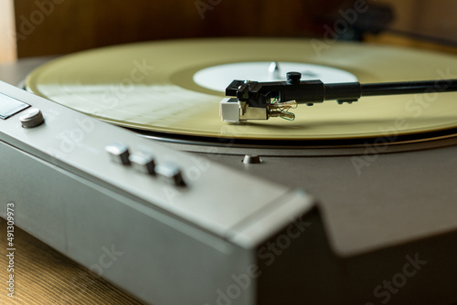 Closeup view of a tonearm and turntable playing color vinyl record.