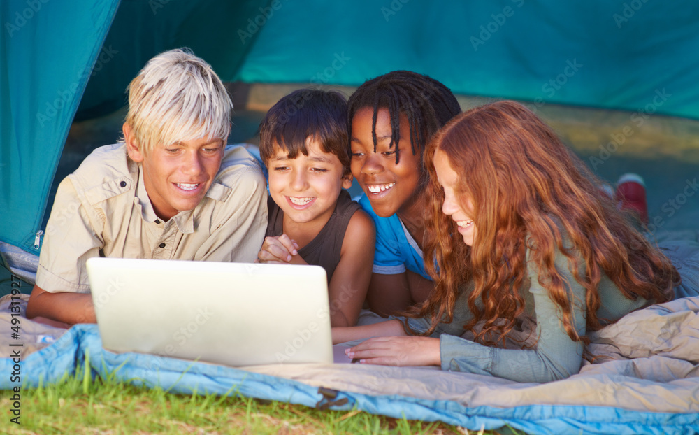 Always connected, no matter where they are - Modern technology. Children enjoying using a laptop while out camping in a tent. Always connected, no matter where they are - Modern technology. Children enjoying using a laptop while out camping in a tent.