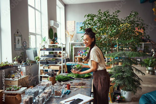 Fotografie Merry attractive florist holding a polyhedron florarium with succulents
