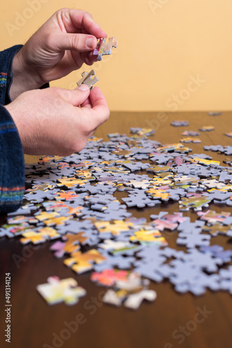 Hands of an adult man in pajamas puts the pieces of a puzzle together. Hobbies.
