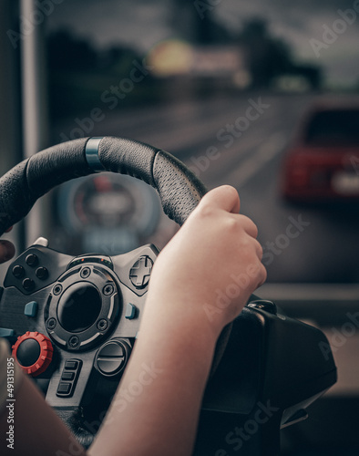 Technology, gaming, entertainment and people concept - young man playing car racing video game at home and steering wheel