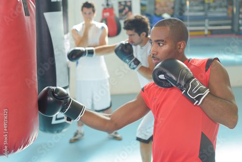african black male boxer punching ball wearing gloves in gym