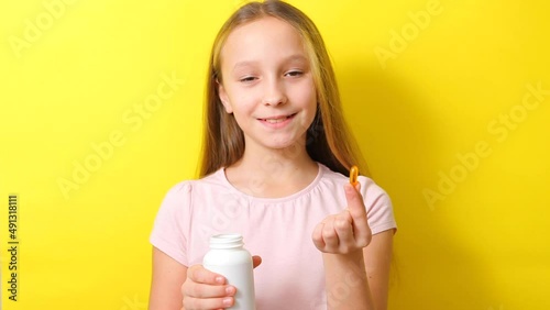 Teenage girl takes omega 3 capsules on a colored background close-up