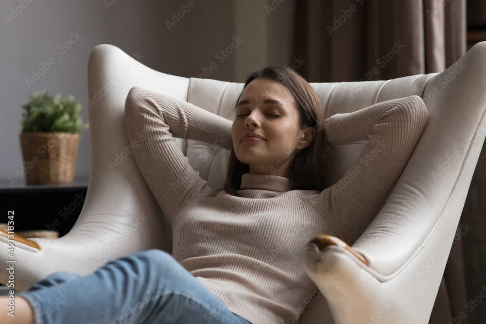 Serene young woman leaned on cozy leather armchair, relax alone at home with eyes closed, put hands behind head enjoy repose, breath fresh conditioned air inside. No stress, carefree leisure concept Serene young woman leaned on cozy leather armchair, relax alone at home with eyes closed, put hands behind head enjoy repose, breath fresh conditioned air inside. No stress, carefree leisure concept