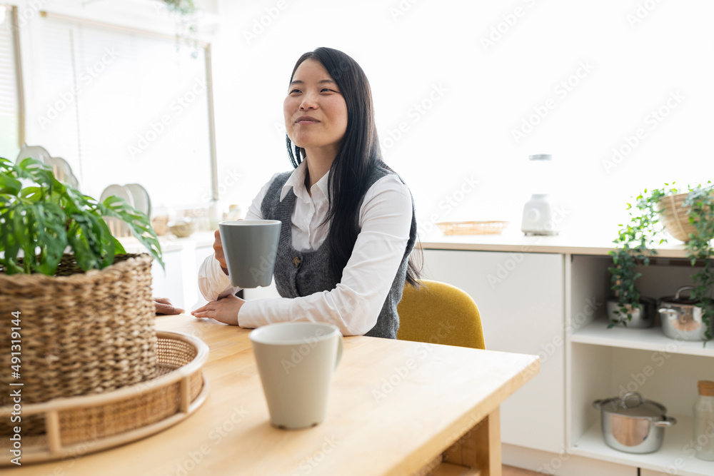 asian woman with cup of coffee at home in the kitchen asian woman with cup of coffee at home in the kitchen