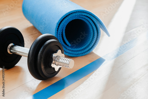Fototapeta Naklejka Na Ścianę i Meble -  Blue color dumbbells and gym mat on wooden surface. Concept of rehabilitation and sport training equipment