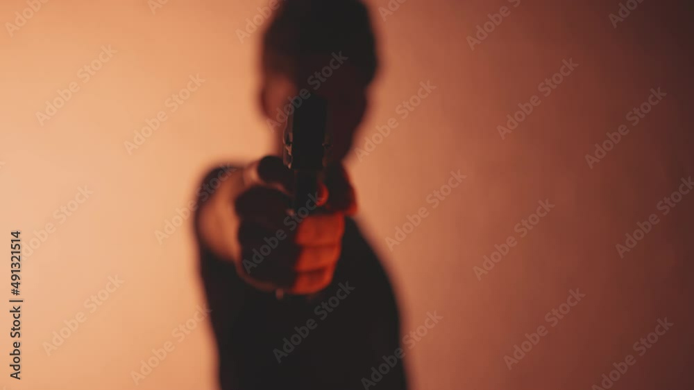 Silhouette of anonymous man pointing a hand gun towards the camera Silhouette of anonymous man pointing a hand gun towards the camera