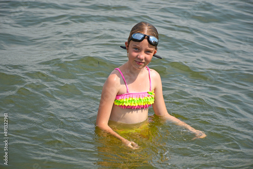 Young small tired 9 years old girl swimmer on finish line after open water competition for children. Sport and activity for kids. Swimming competition. Healthy lifestyle from childhood