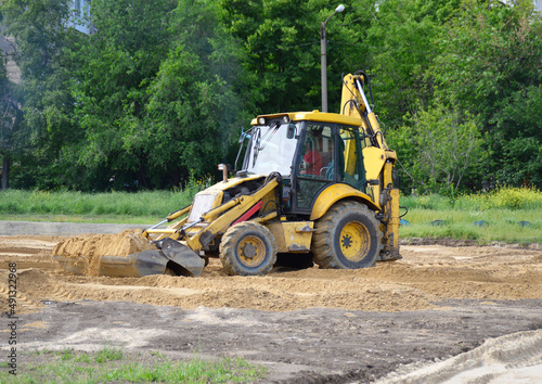 A backhoe pushing a pile of sand.This is a type of excavating equipment consisting of a tractor-like unit fitted with a loader-style shovel-bucket on the front and a backhoe on the back