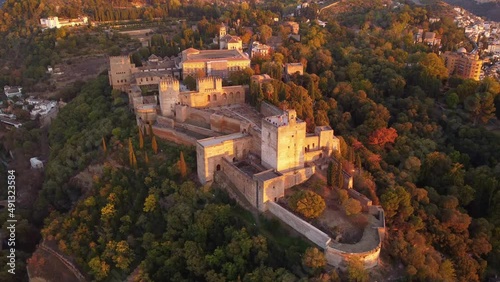 Dramatic aerial drone footage of the famous Alhambra palace and fortress in Granada, Andalusia, in Spain at sunset. Shot with a forward and tilt down motion. 