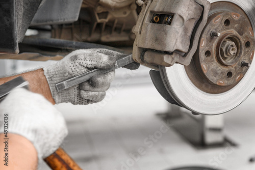 change the old drive to the Brand new brake disc on car in a garage. Auto mechanic repairing