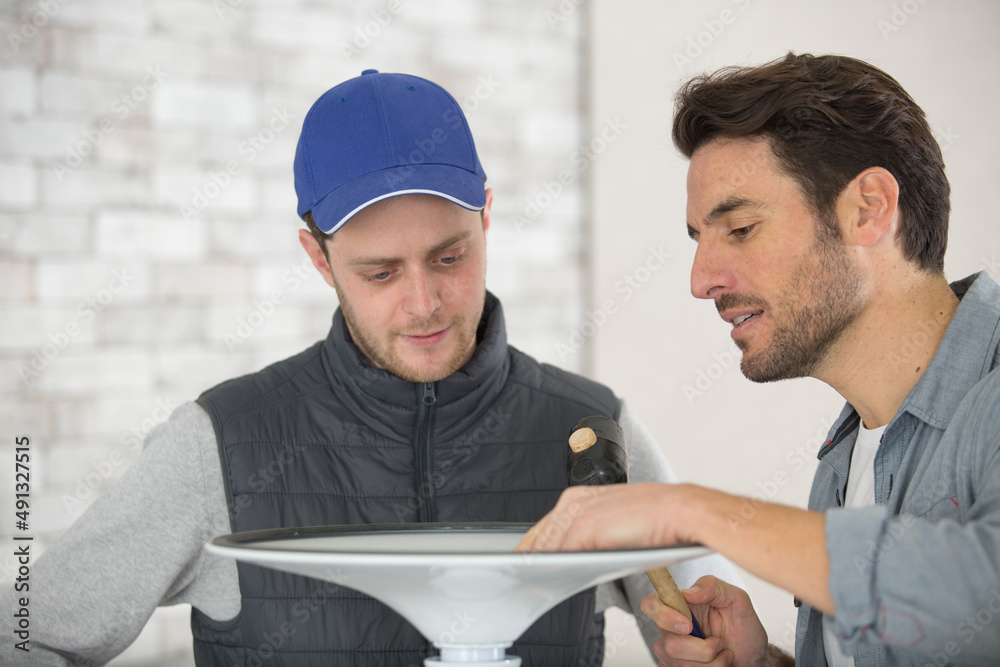 man with apprentice assembling metal stool man with apprentice assembling metal stool