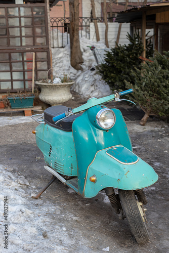 old motor scooter stands in the yard of the house