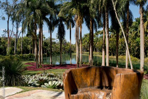 
Lindo jardim com grande tronco de árvore trabalhado rusticamente e feito de banco, linda paisagem ao fundo, com lago artificial, muitas palmeiras e vegetação ao redor no museu a céu aberto de Minas G photo