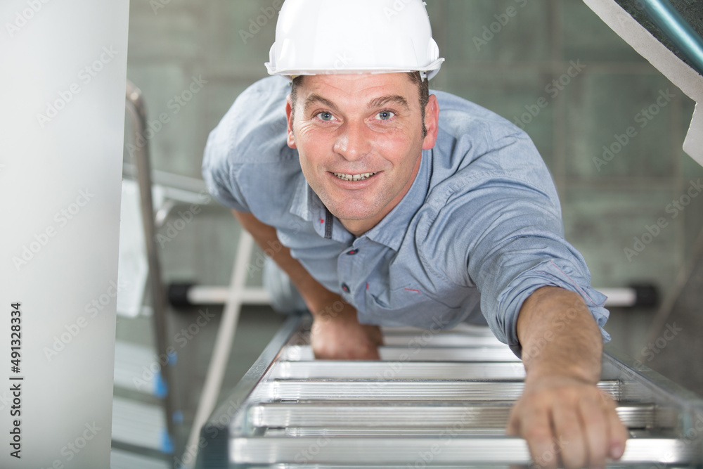 happy male builder standing on ladder happy male builder standing on ladder