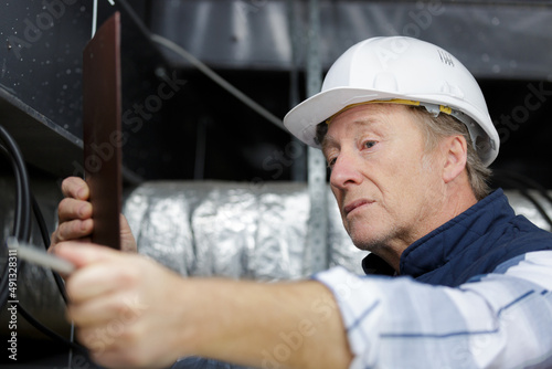 male senior worker builder with helmet working in ceiling