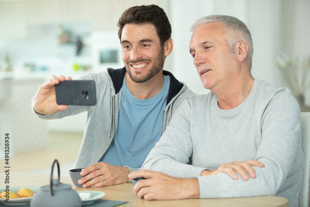 cheerful young man taking a selfie with his elderly father