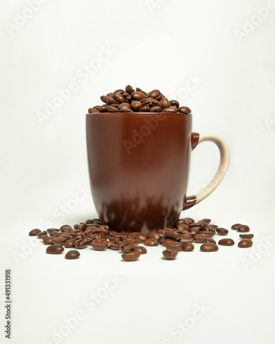 Coffee beans spilled out of the brown mug. On a white background.
