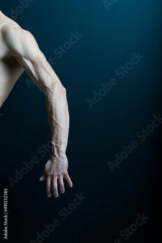 Strong hand of faceless male with arm stretching on dark background.