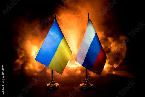 Concept of crisis of war and political conflicts between countries. Russia and Ukraine small flags on dark burning background. photo