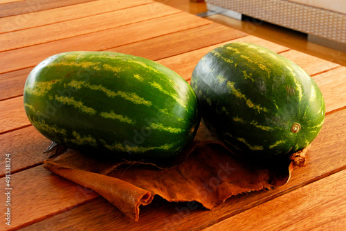 watermelon, pair of green watermelons on a wooden table in home interior photo