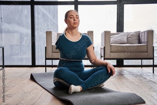 Caucasian woman with amputee arm meditating at home in the morning and practicing yoga photo