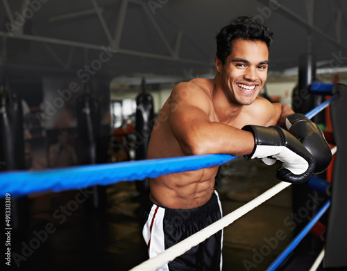 Hes found his place in the boxing ring. Portrait of a young man leaning on the ropes of a boxing ring.