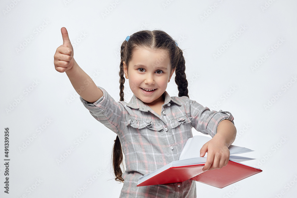 little girl holds a red book in her hands and gives a thumbs up little girl holds a red book in her hands and gives a thumbs up
