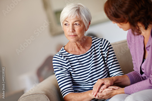 Worried about the future. Shot of a woman sitting beside her elderly mother at home. photo