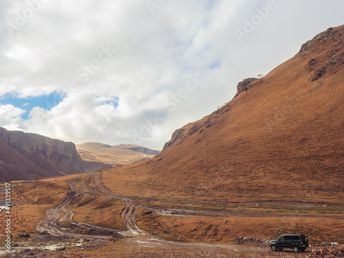 Caucasian mountain gorge with SUV driving off-road on a cloudy autumn day © jockermax3d