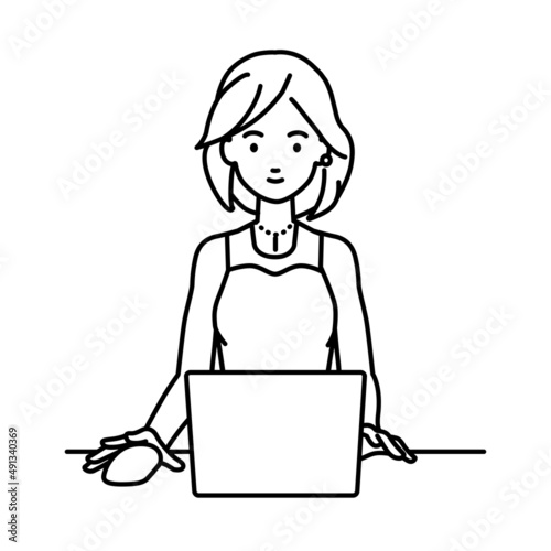 デスクで座ってPCを使っているドレスの女性