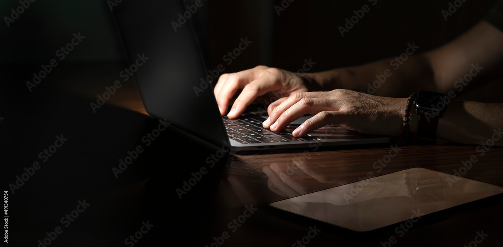 Cropped shot of businessman working on Laptop at desk. Dark tone with copy space. Cropped shot of businessman working on Laptop at desk. Dark tone with copy space.