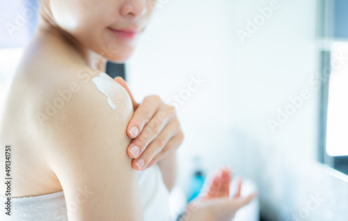 Cropped shot of woman applying lotion (or moisturizer) on her skin for softening the skin. Some skincare products available in multiple formats, such as lotions, gels, creams etc.