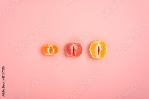 tangerine, grapefruit and orange cut in half on a peach background as a symbol of the vagina and female fertility photo