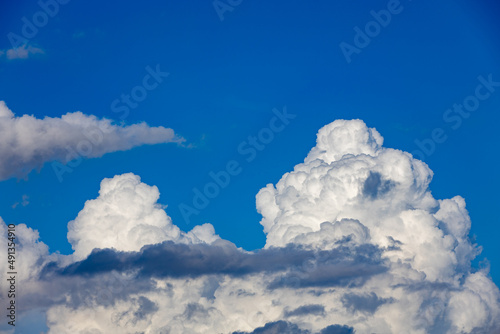 thick white cummulus clouds on a sunny day against a bright blue sky. 
absorbent cotton clouds indicating bad weather. blue background on a sunny day.  photo