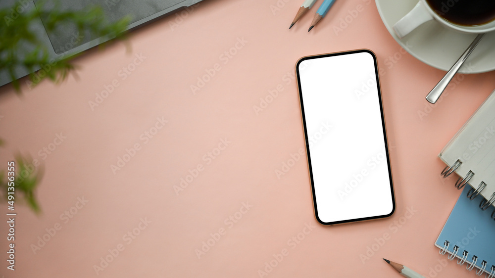 Obraz premium A pastel pink workspace background with smartphone mockup