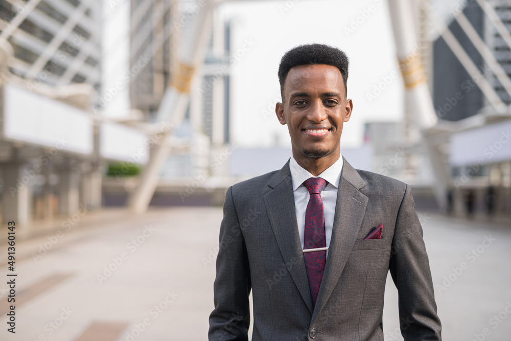 Portrait of handsome young African businessman outdoors in city