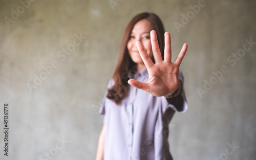A young asian woman outstretched hand and showing stop hand sign