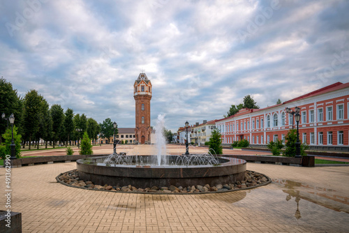 View of the fountain on Cathedral Square (Sobornaya) and the water tower on an early cloudy summer morning, Staraya Russa, Novgorod region, Russia photo